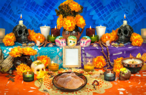a day of the dead altar with candles, marigolds, sugar skulls and day of the dead decor