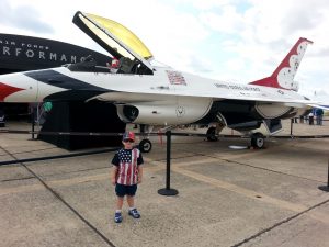 young boy wearing patriotic clothes in front of an air force fighter jet