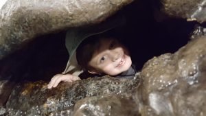 a child peering through a rock formation