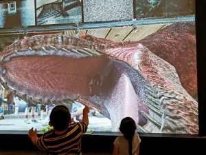 a video dinosaur roaring at children in an interactive display
