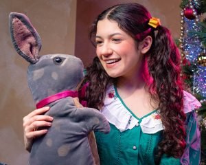 a young actress holding a stuffed rabbit for the Velveteen Rabbit