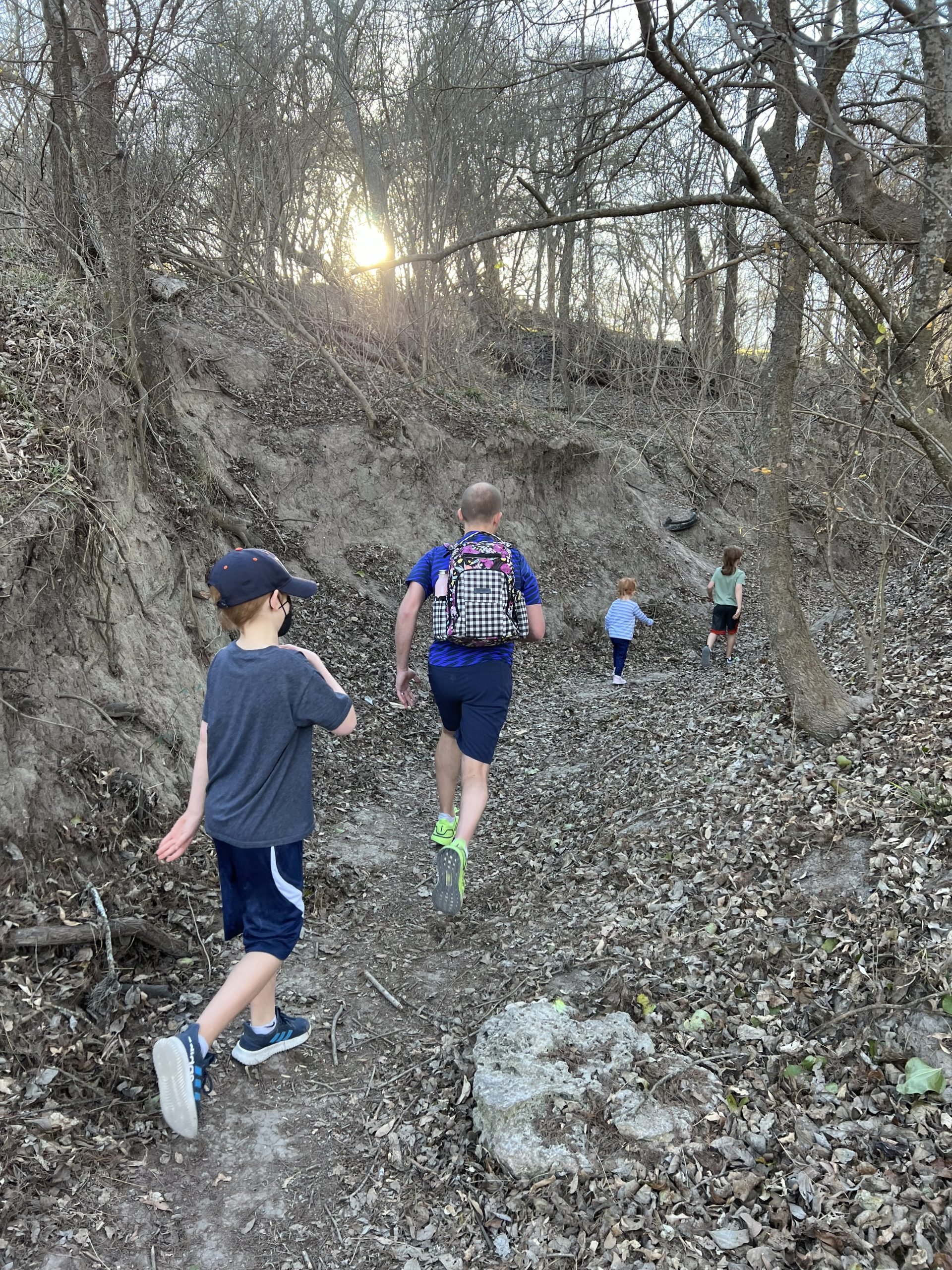An adult and 3 kids walking through a rugged trail