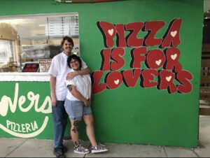 owners in front of pizza restaurant 