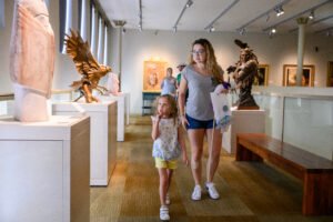 a young girl and her mother enjoy sculptures in a museum