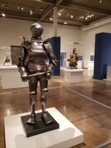 a shiney metal suit of armor featured inside a museum display