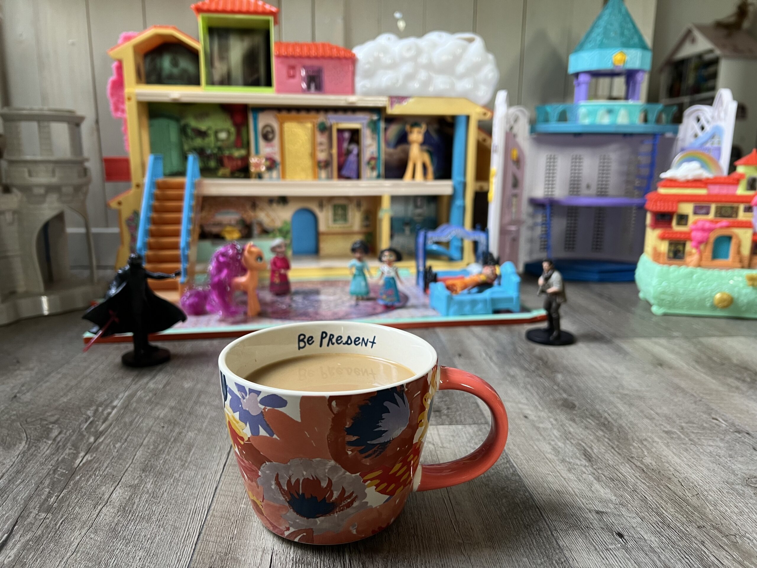 Coffee cup that says “be present” in front of toys 