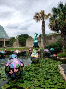 bunny statue and decorated orbs in a pond