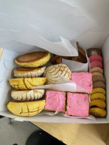 White box of Mexican sweet bread in a variety of colors; pink, yellow, white.